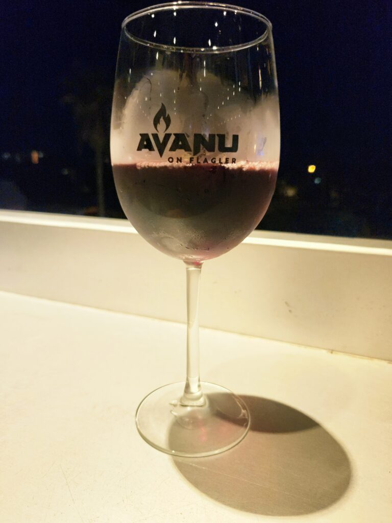 A glass of red wine on the table overlooking Flagler Avenue.