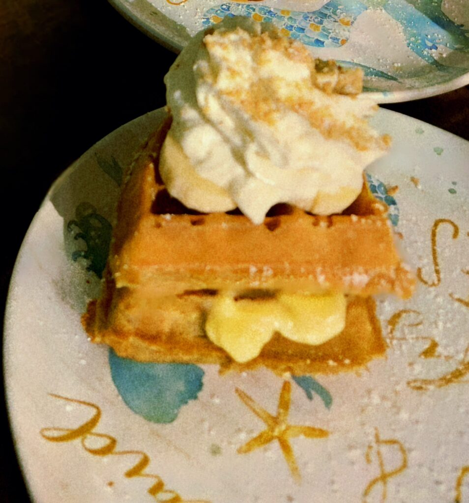 Waffle stack with filling oozing out of the middle, topped with whipped cream and bananas.