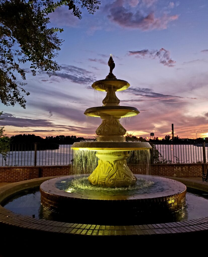 Sunset view of Historic Georgetown SC Harborwalk Fountain at the point where the Harborwalk overlooks the Bay.