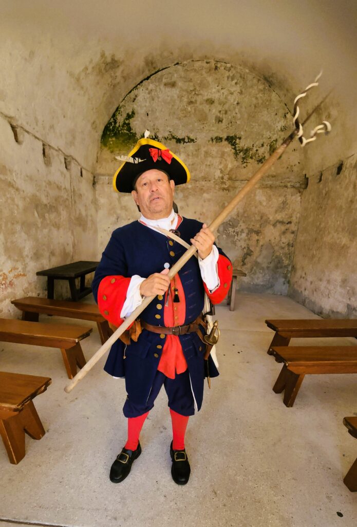 Man in period dress tells stories in an ammunition storage room under the St. Augustine fort.