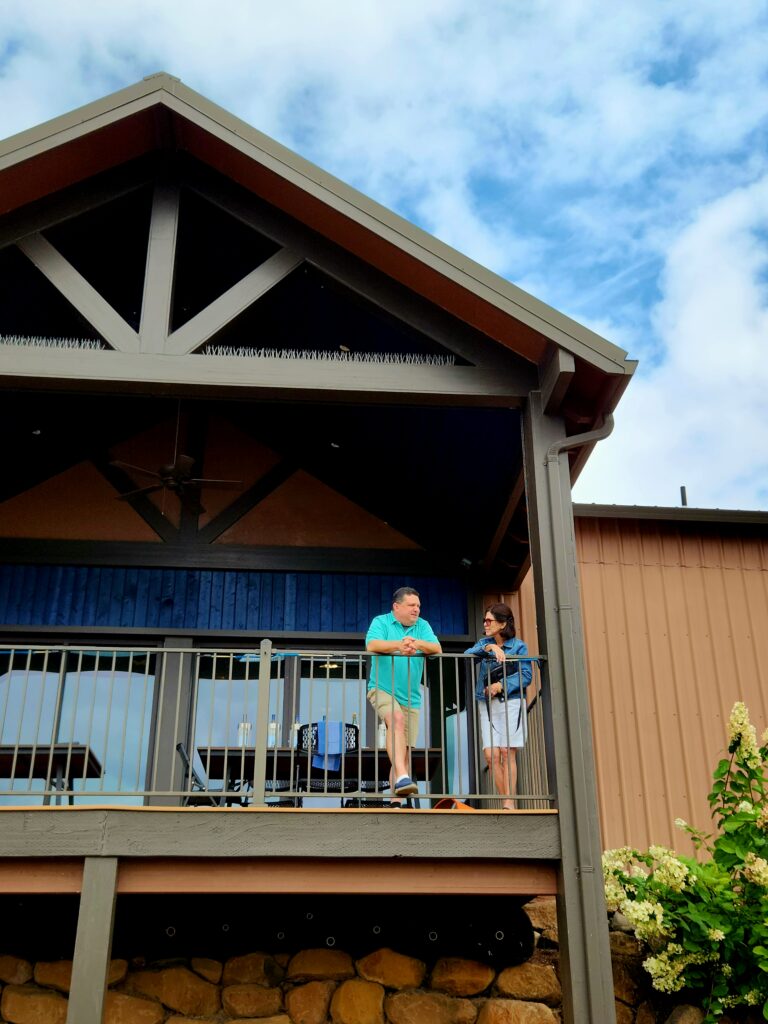 26 Sensational Must-Visit Oregon Wineries in the Willamette Valley 19 Winemaker and visitor on tasting room balcony overlooking Willamette Valley vineyard.