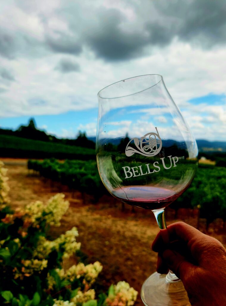 26 Sensational Must-Visit Oregon Wineries in the Willamette Valley 18 Red wine in a Bells Up glass, with winery in the background.
