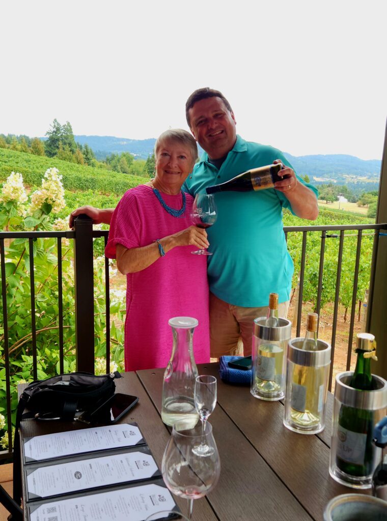 
Author and winemaker overlooking vineyard and toasting with glasses of wine on the deck at Bell's Up Winery in Willamette Valley.