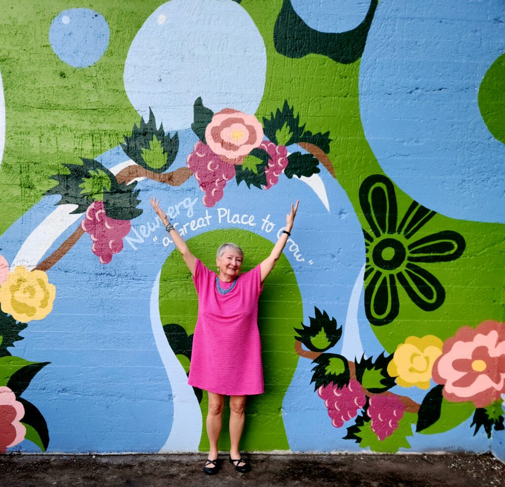 26 Sensational Must-Visit Oregon Wineries in the Willamette Valley 22 Colorful Newberg mural with writer Jo in front.