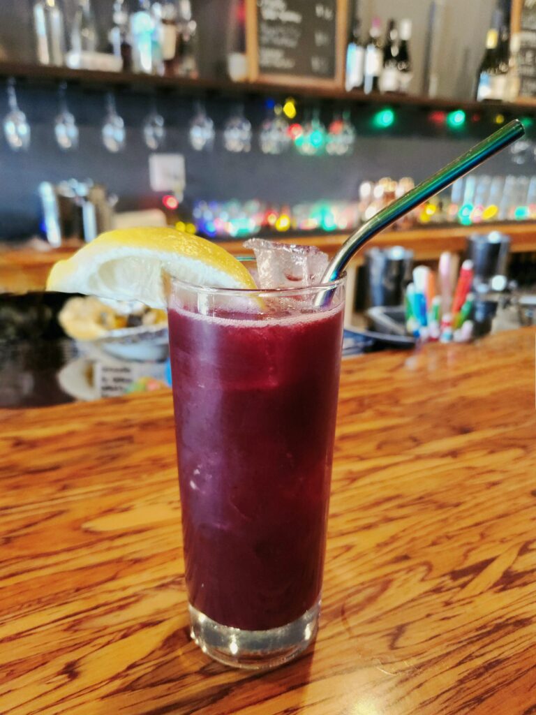 Spend 11 Awesome Days in the Willamette Valley 24 Blueberry Lemonade drink in a tall glass, with a straw and lemon wedge.
