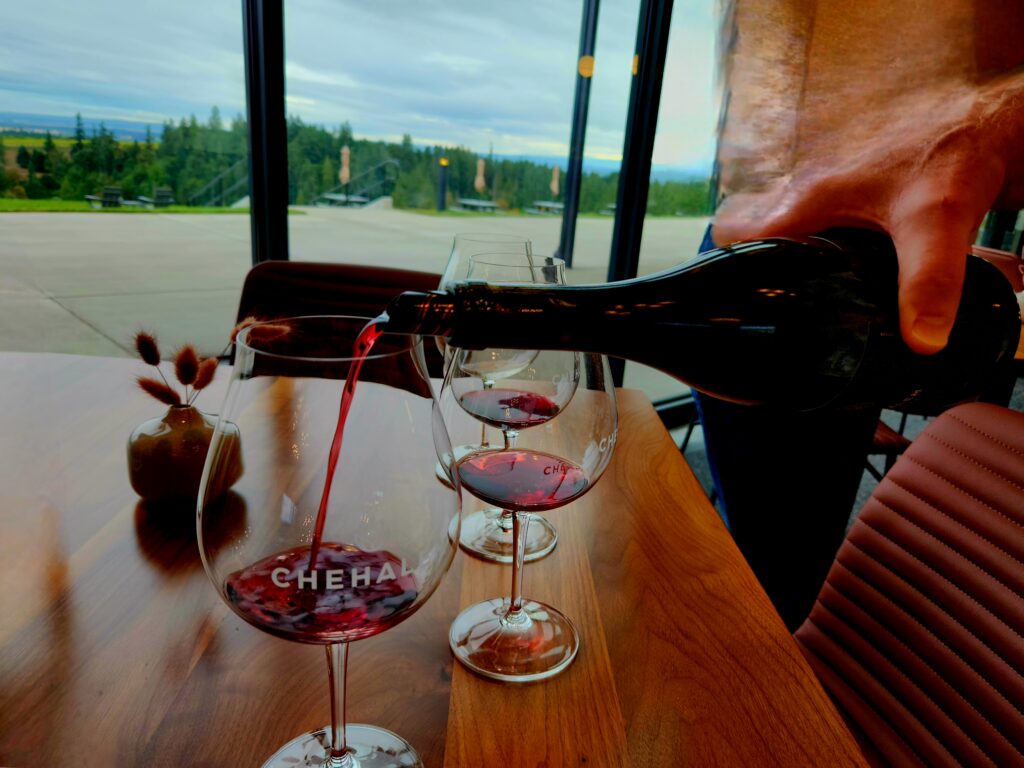 26 Sensational Must-Visit Oregon Wineries in the Willamette Valley 8 Pouring red wine into a logo Chehalem stemmed glass.