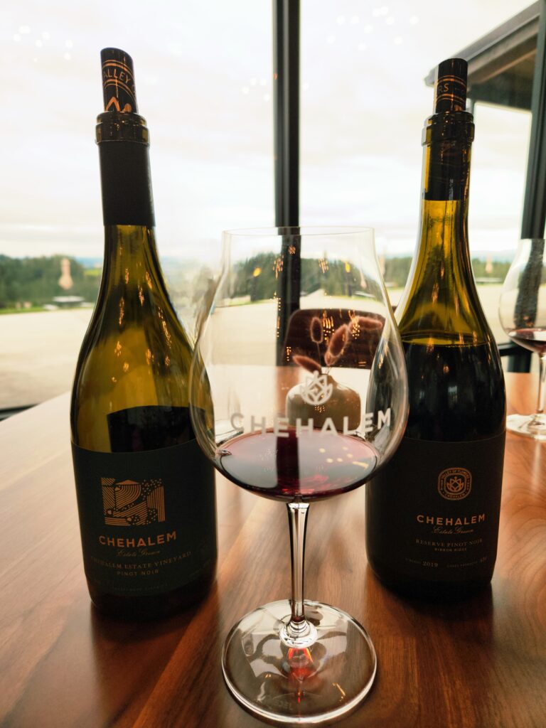 26 Sensational Must-Visit Oregon Wineries in the Willamette Valley 10 Two Pinot Noirs with a Chehalem wine glass.