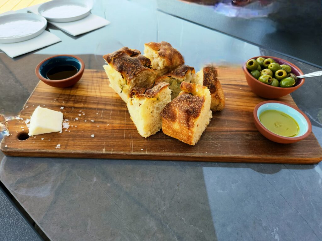26 Sensational Must-Visit Oregon Wineries in the Willamette Valley 60 A board with chunks of bread, a wedge of cheese, and a small bowl of olives.