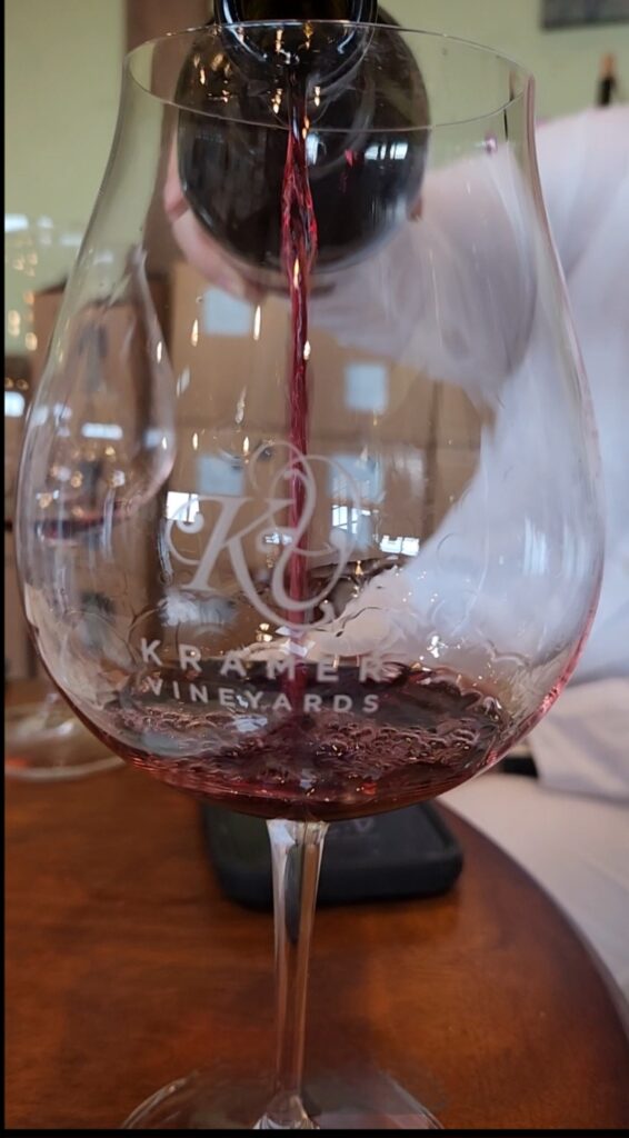 26 Sensational Must-Visit Oregon Wineries in the Willamette Valley 76 Red wine being poured into Kramer Vineyards logo stem glass.