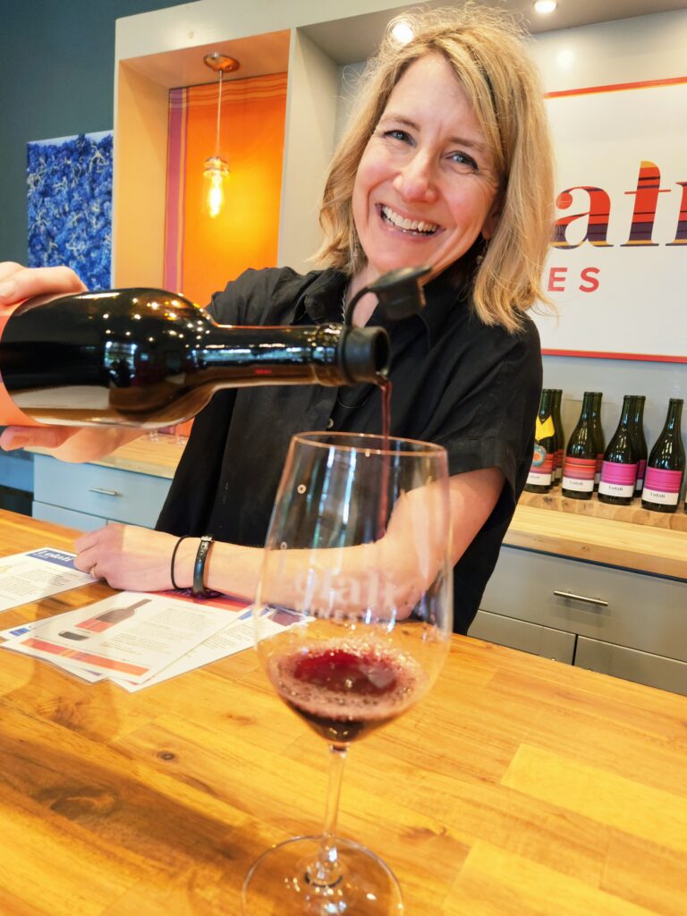 Woman with a huge smile pours a red wine.