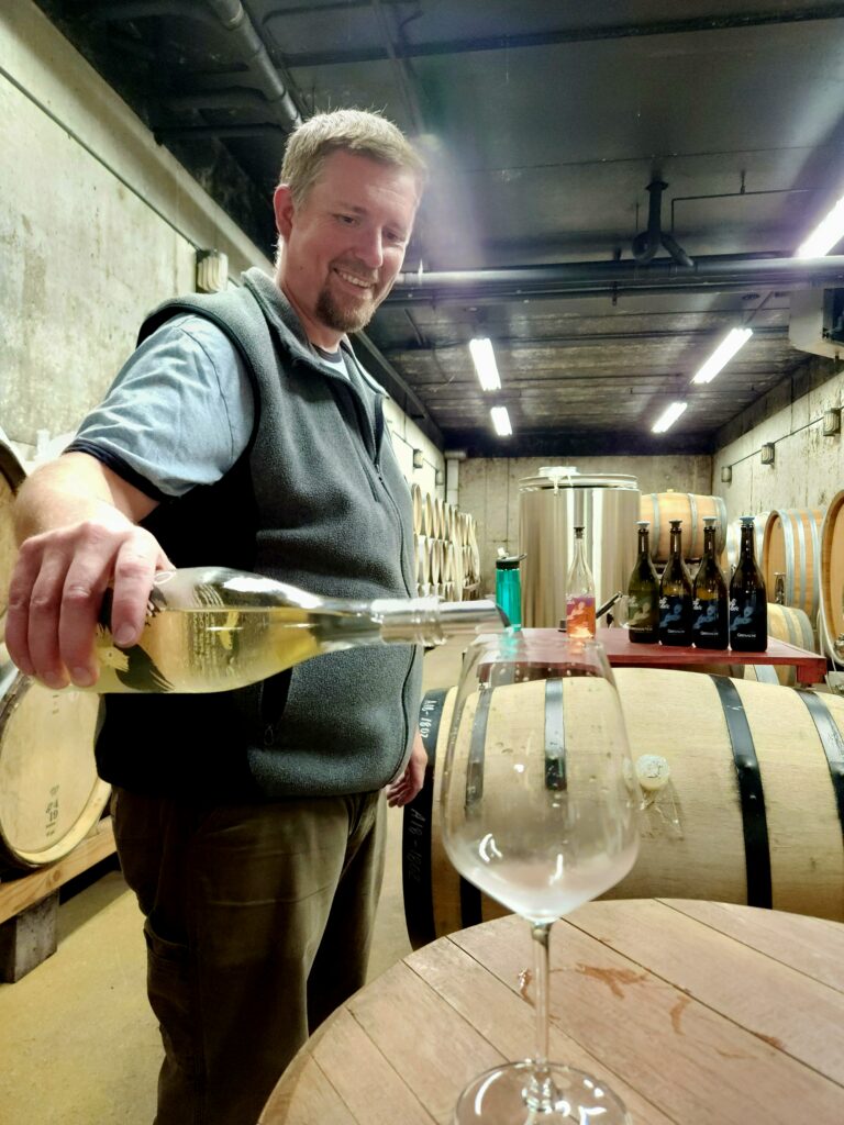 26 Sensational Must-Visit Oregon Wineries in the Willamette Valley 36 Man pouring wine in his barrel room.