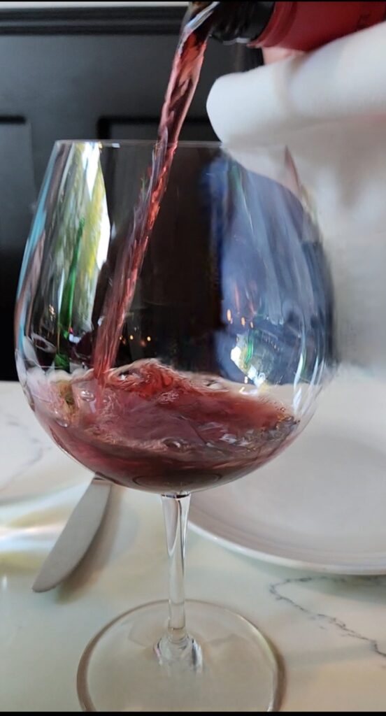 26 Sensational Must-Visit Oregon Wineries in the Willamette Valley 101 Red wine in a glass, with empty white plates on the table.