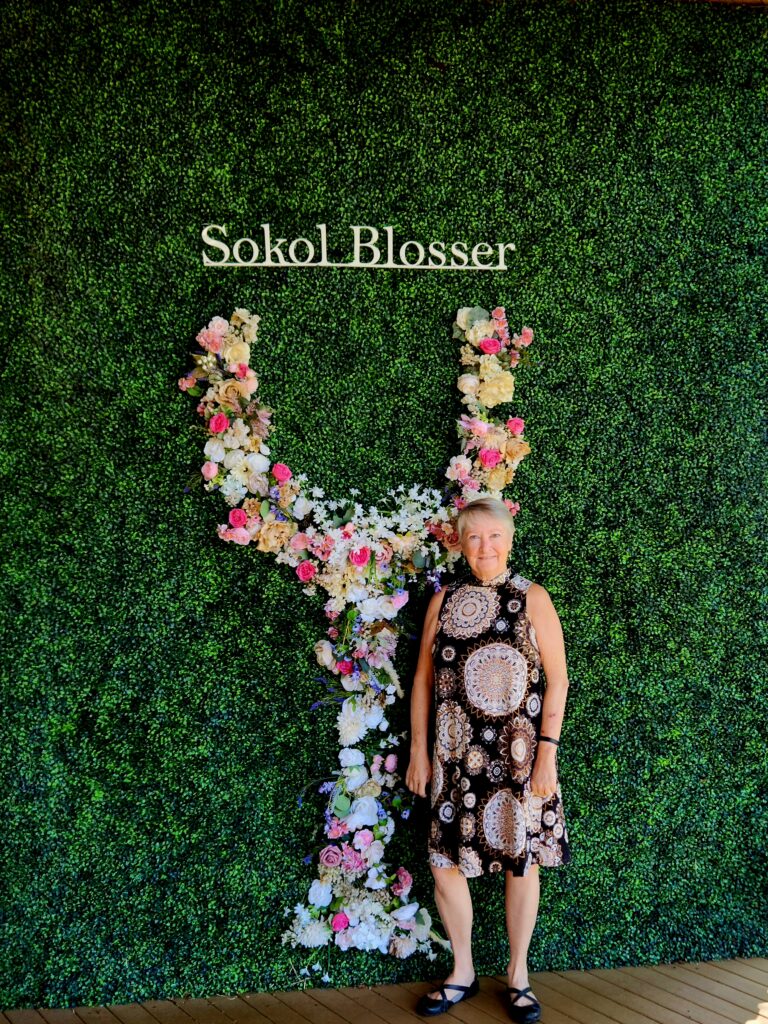 26 Sensational Must-Visit Oregon Wineries in the Willamette Valley 44 Writer in front of a wine glass designed of flowers on a greenery backcground.