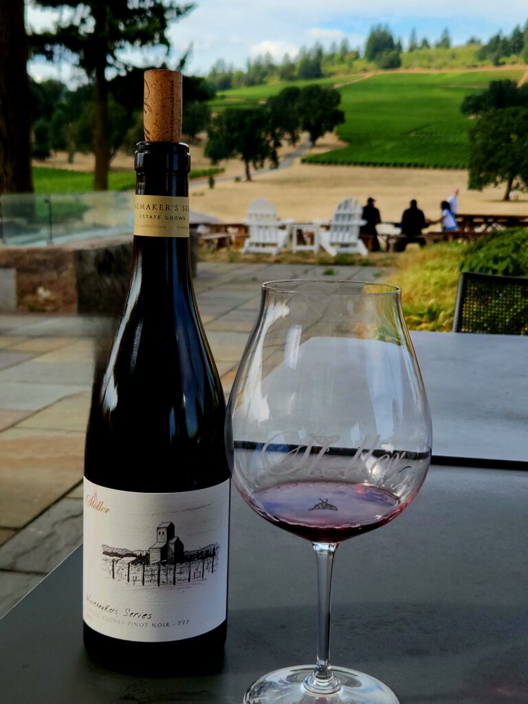 26 Sensational Must-Visit Oregon Wineries in the Willamette Valley 52 A bottle of Pinot Noir and pour on outdoor table.