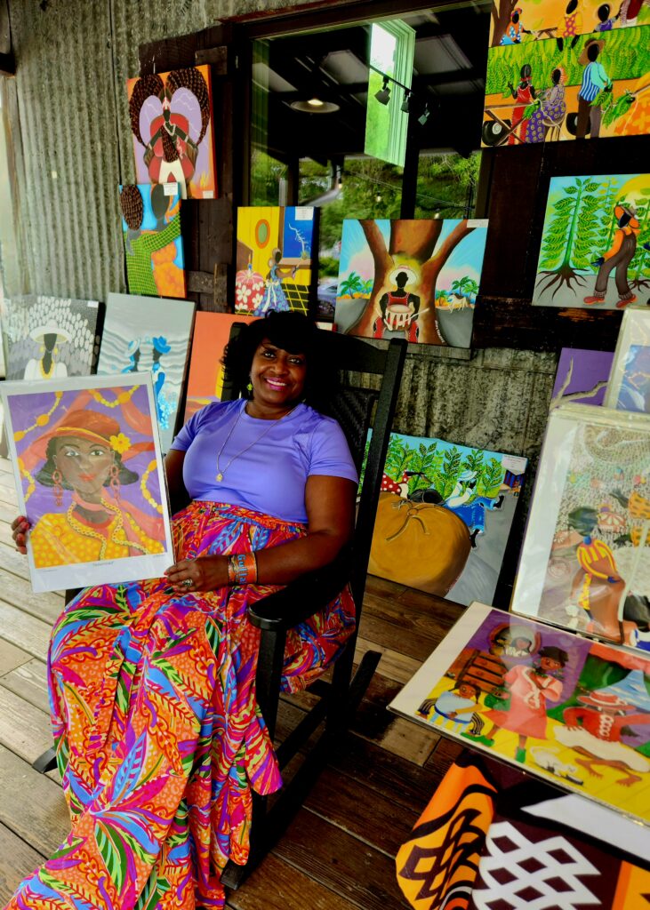 2 Islands, a Lighthouse, & Secret Magic of the Lowcountry 60 Black woman on porch displaying her colorful art pieces.