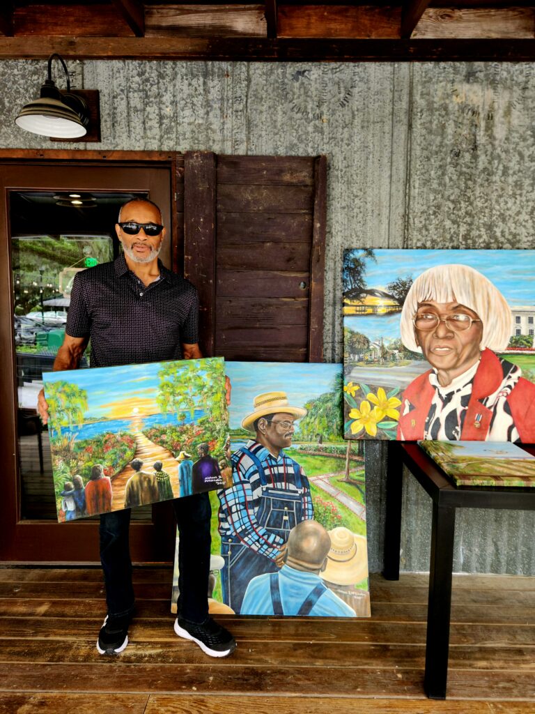 2 Islands, a Lighthouse, & Secret Magic of the Lowcountry 59 Colorful Gullah Art and the artist holding up one piece.