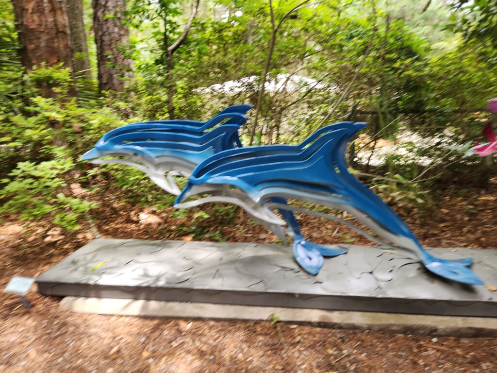 2 Islands, a Lighthouse, & Secret Magic of the Lowcountry 63 Dolphins of steel race toward the water in a sculpture garden.