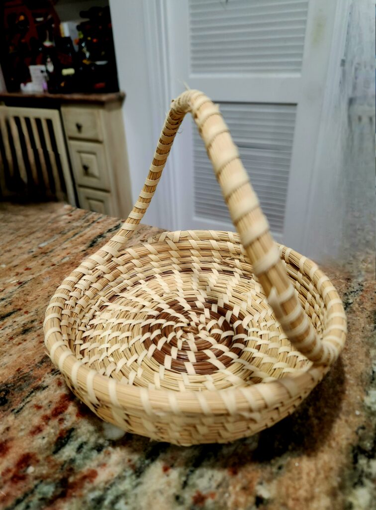 Discovering Powerful, Enduring Legacies of Juneteenth on the Gullah Trail 4 A small sweetgrass basket with an arched and twisted handle.