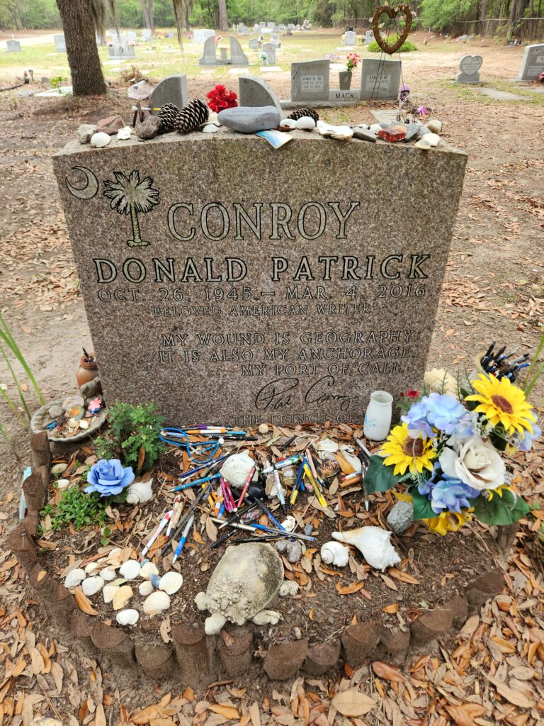 2 Islands, a Lighthouse, & Secret Magic of the Lowcountry 20 Pat Conroy's granite headstone under a live oak, with the ground covered in ink pens.