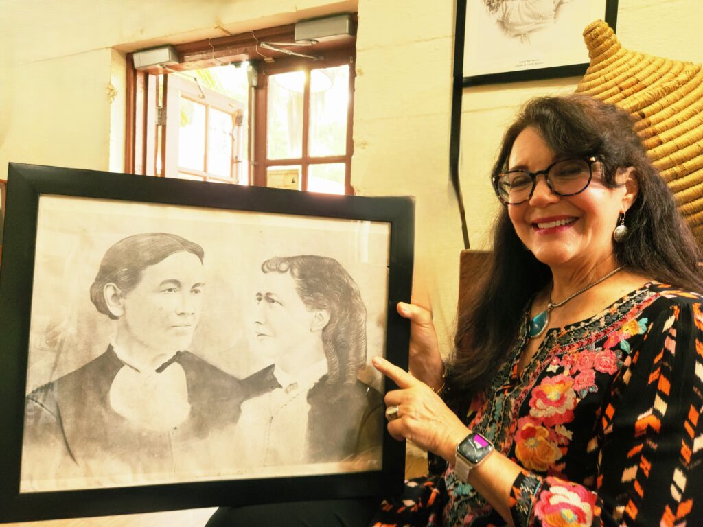 2 Islands, a Lighthouse, & Secret Magic of the Lowcountry 12 Woman holding a framed pencil sketch of the two women who co-founded Penn School.