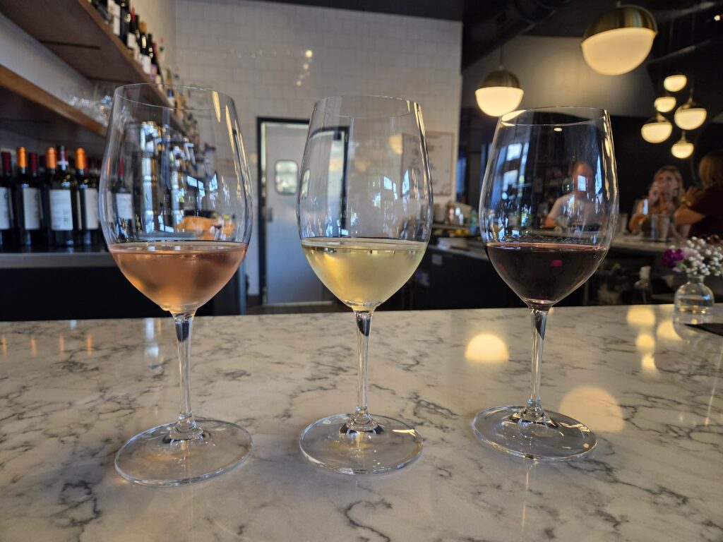 Greensboro: Big, Unexpected Adventures From 1781 Battlefield to Jeansboro 43 Three wine glasses filled with rose', white, and red.