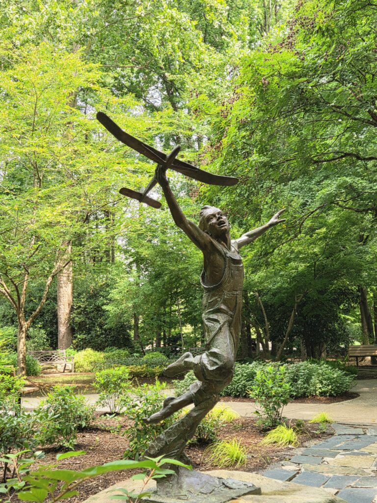 Statue of a boy playing with his airplane.