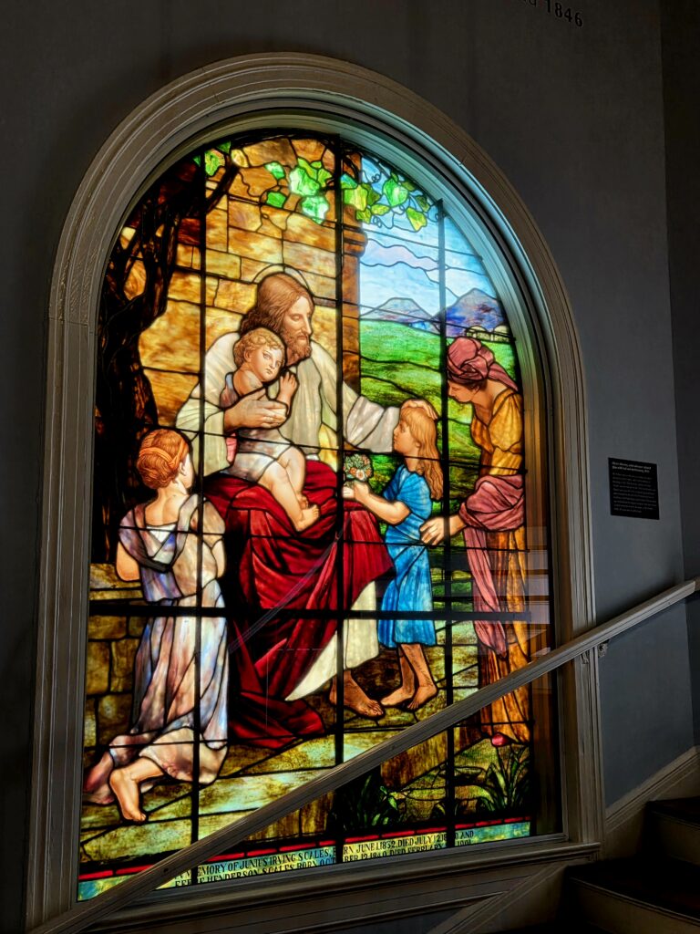 Greensboro: Big, Unexpected Adventures From 1781 Battlefield to Jeansboro 22 Original stained glass window depicting Jesus surrounded by children.
