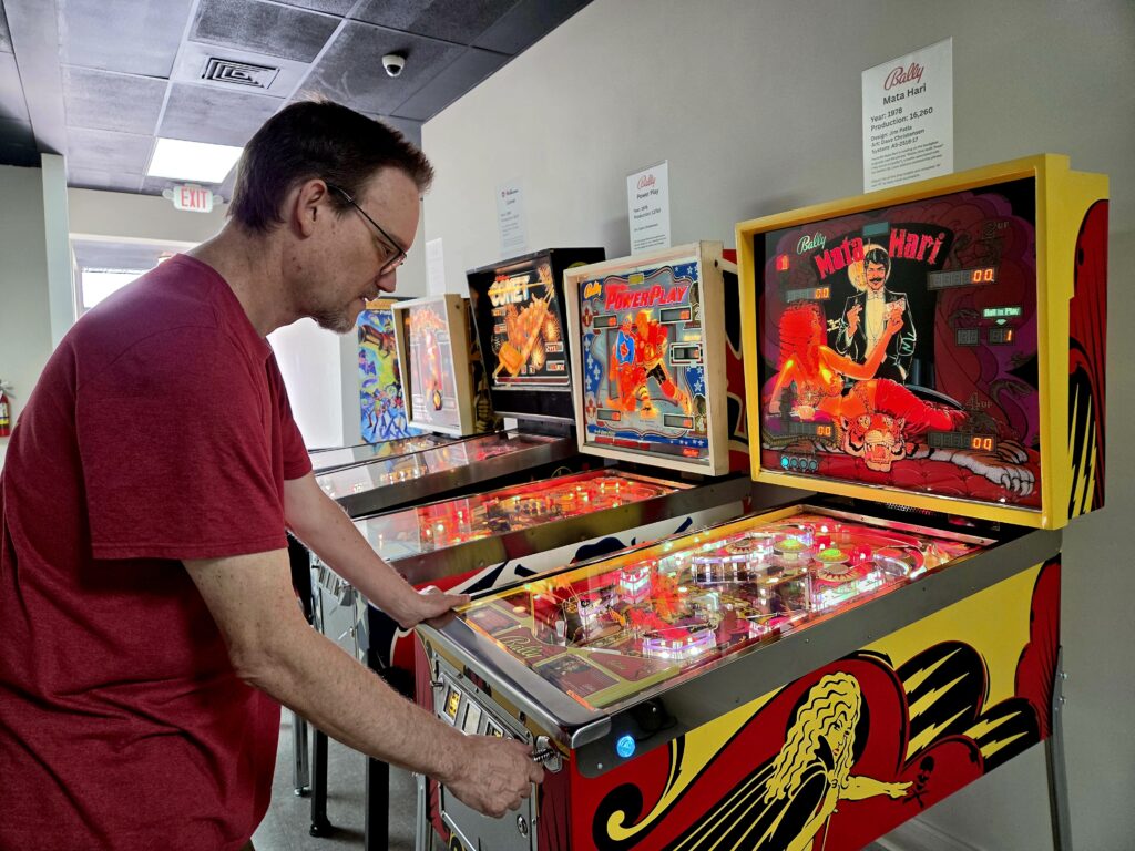 Greensboro: Big, Unexpected Adventures From 1781 Battlefield to Jeansboro 33 Man playing a colorful pinball machine.