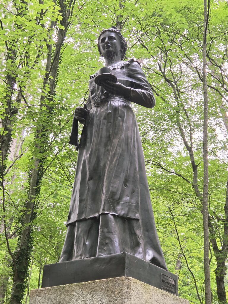 Greensboro: Big, Unexpected Adventures From 1781 Battlefield to Jeansboro 13 A bronze statue of a woman holding a teacup and saucer, with a towel draped over her other arm.