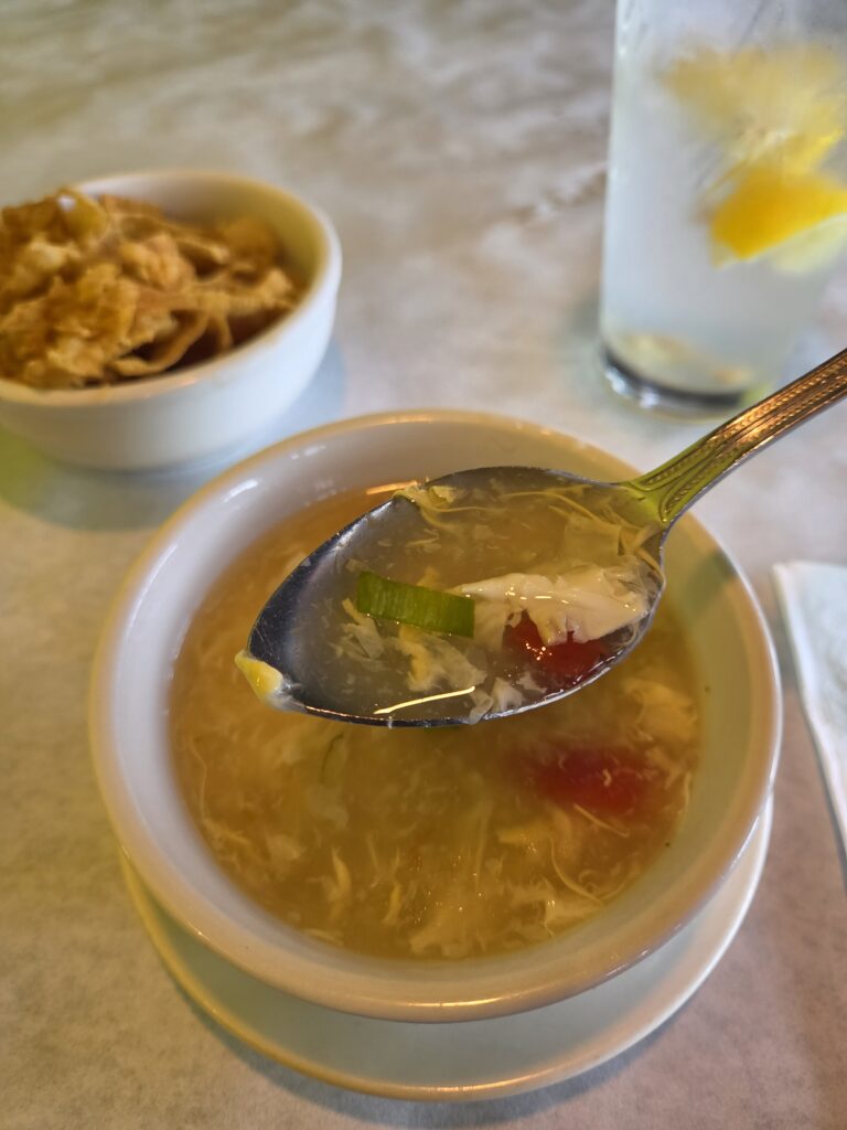 Greensboro: Big, Unexpected Adventures From 1781 Battlefield to Jeansboro 37 A cup of Tomato Egg Drop Soup with the first bite in a soup spoon.